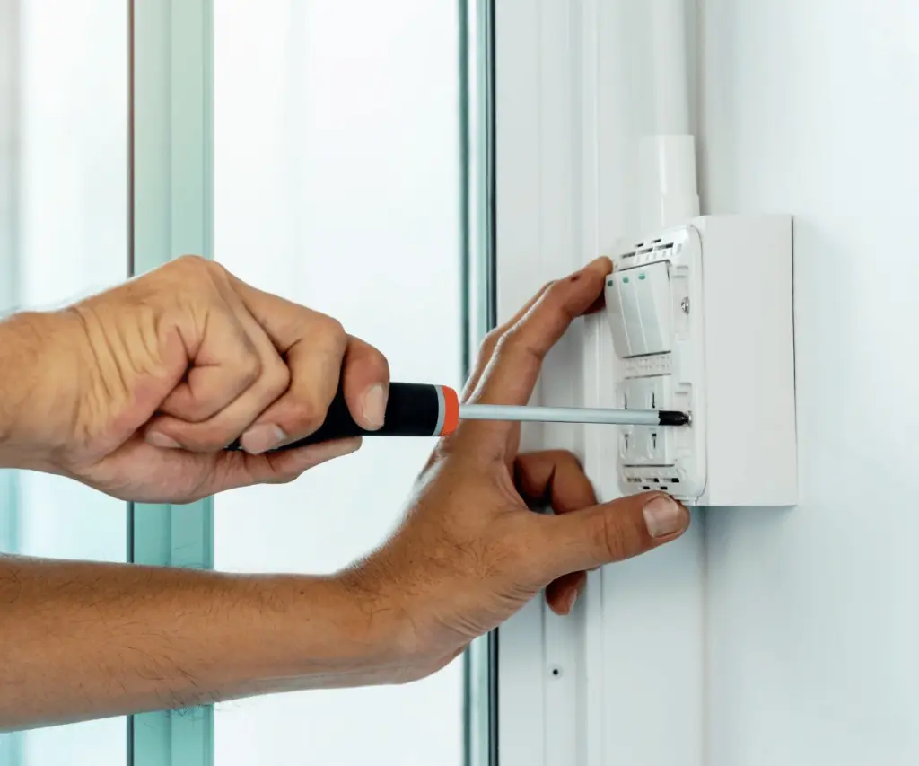 Electrician fitting modern thermostat and testing controls