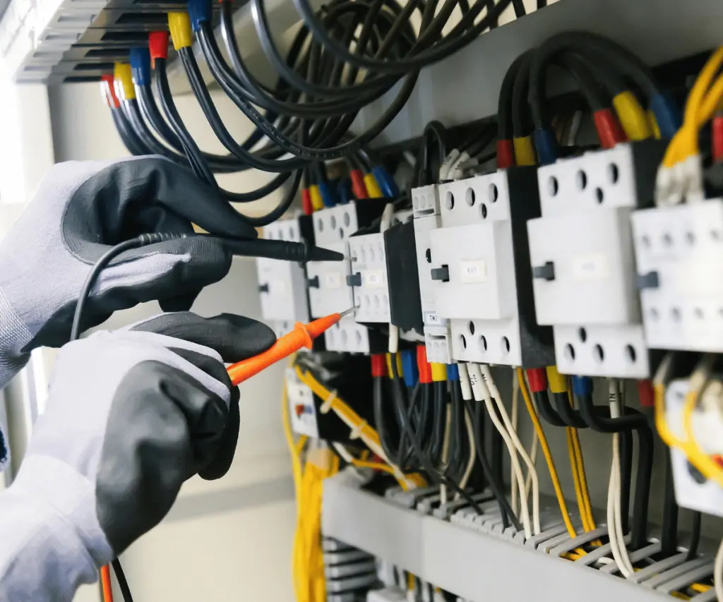 Electrician inspecting electrical panel wiring for safety compliance